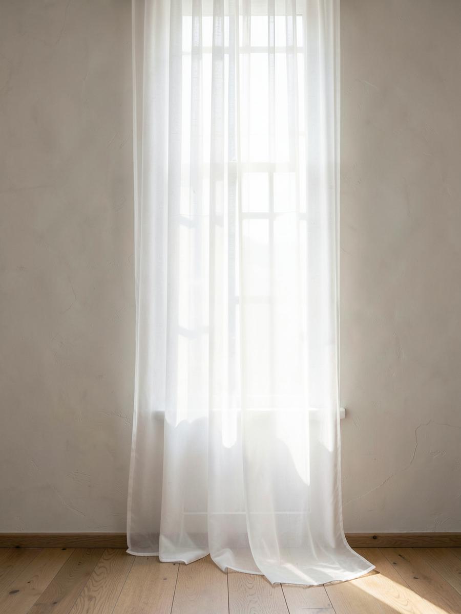 Voilage translucide filtrant la lumière devant une fenêtre